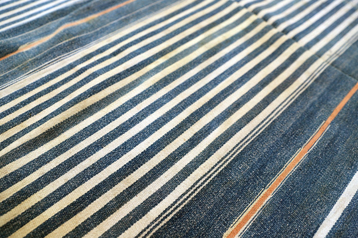 Close-up of a denim fabric with horizontal stripes in blue, beige, and brown.