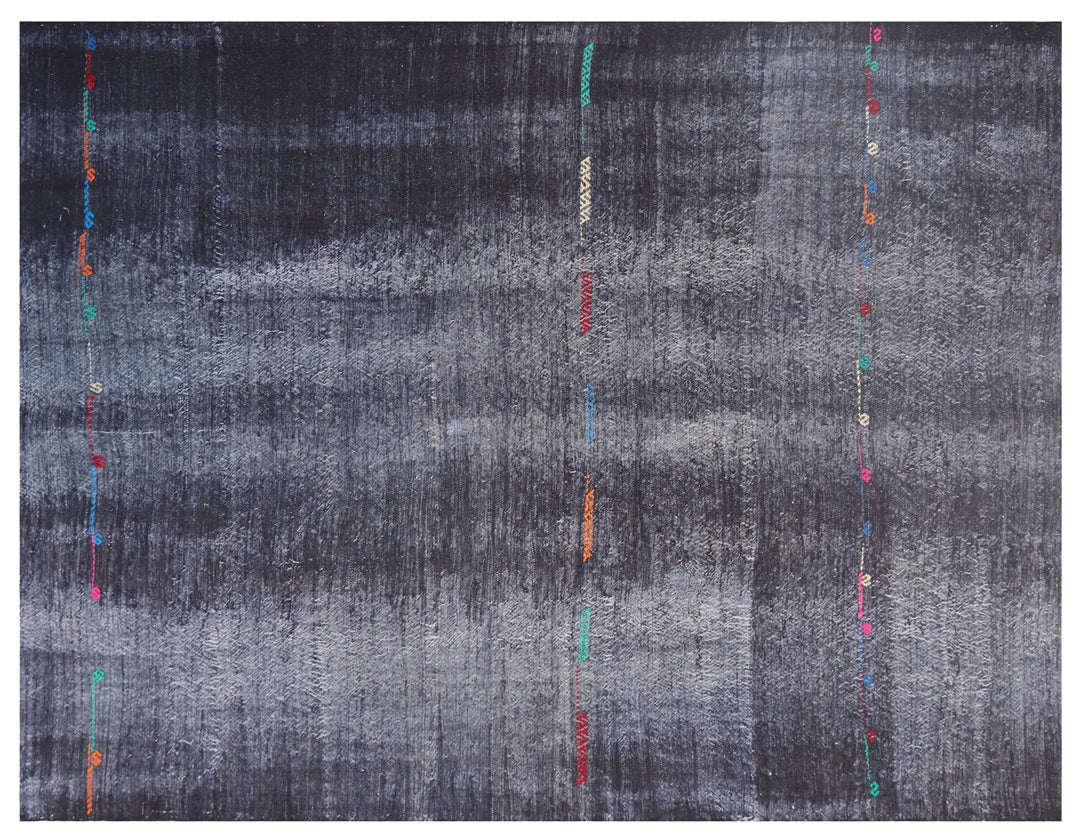 An abstract square textile or rug with a distressed charcoal gray and black background, featuring vertical rows of small colorful embroidered or printed accents in red, orange, teal, pink, and white.