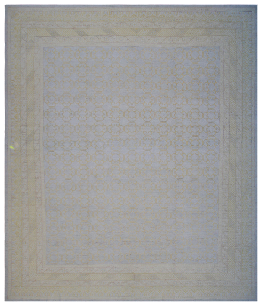A rectangular rug with a large geometric pattern in soft blue and gold colors, appearing to be made of a wool on cotton material.