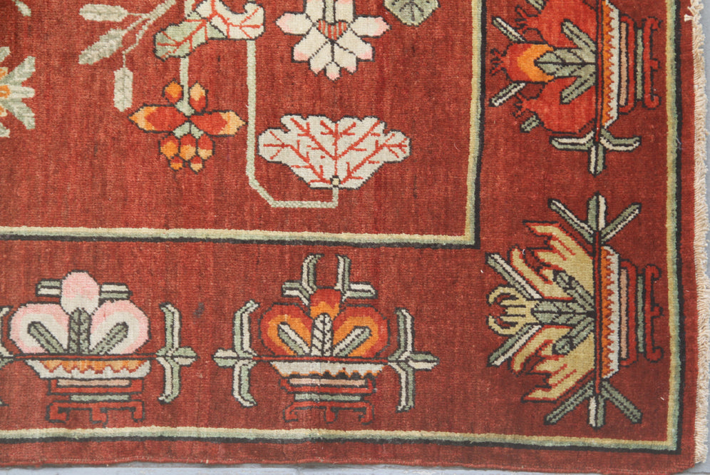 Rare 5x9 antique Yarkand Samarkand hand-knotted wool rug featuring a vase design on a reddish-purple abrash field by Ariana Rugs.