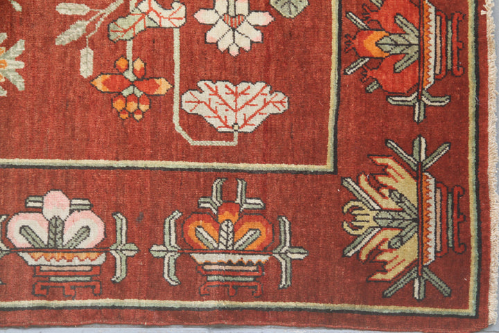 Rare 5x9 antique Yarkand Samarkand hand-knotted wool rug featuring a vase design on a reddish-purple abrash field by Ariana Rugs.
