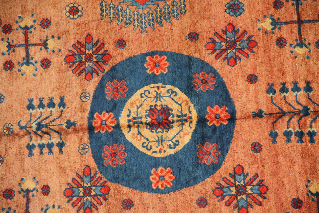 Authentic antique hand-knotted Samarkand Khotan wool area rug featuring geometric medallions in blue, rust, and terracotta on a peach and ivory field