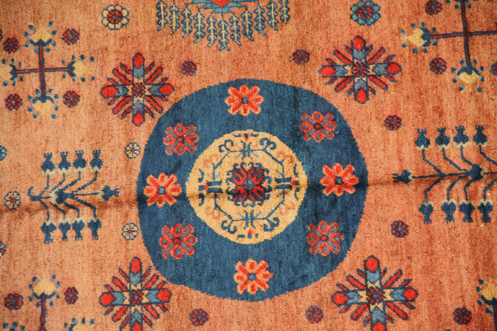 Authentic antique hand-knotted Samarkand Khotan wool area rug featuring geometric medallions in blue, rust, and terracotta on a peach and ivory field