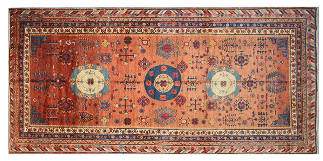 Authentic antique hand-knotted Samarkand Khotan wool area rug featuring geometric medallions in blue, rust, and terracotta on a peach and ivory field