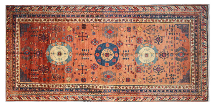 Authentic antique hand-knotted Samarkand Khotan wool area rug featuring geometric medallions in blue, rust, and terracotta on a peach and ivory field