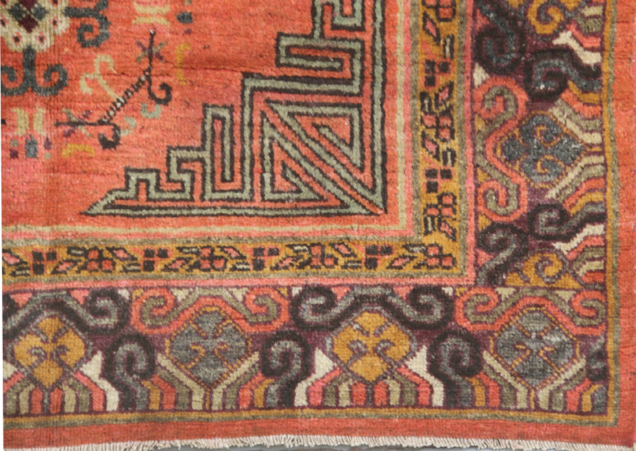 Authentic antique hand-knotted Samarkand Khotan wool area rug featuring two large grey central medallions on a deep red field with salmon brown accents