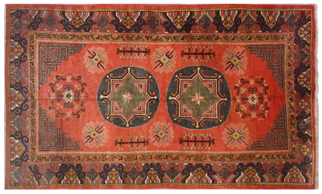 Authentic antique hand-knotted Samarkand Khotan wool area rug featuring two large grey central medallions on a deep red field with salmon brown accents