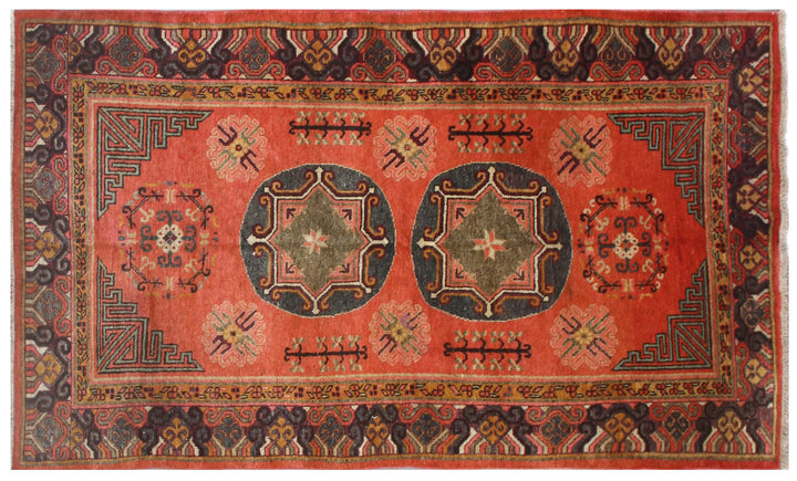 Authentic antique hand-knotted Samarkand Khotan wool area rug featuring two large grey central medallions on a deep red field with salmon brown accents