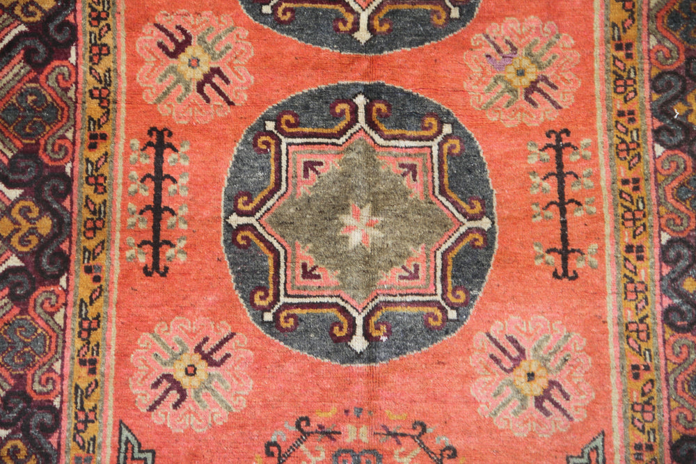 Authentic antique hand-knotted Samarkand Khotan wool area rug featuring two large grey central medallions on a deep red field with salmon brown accents