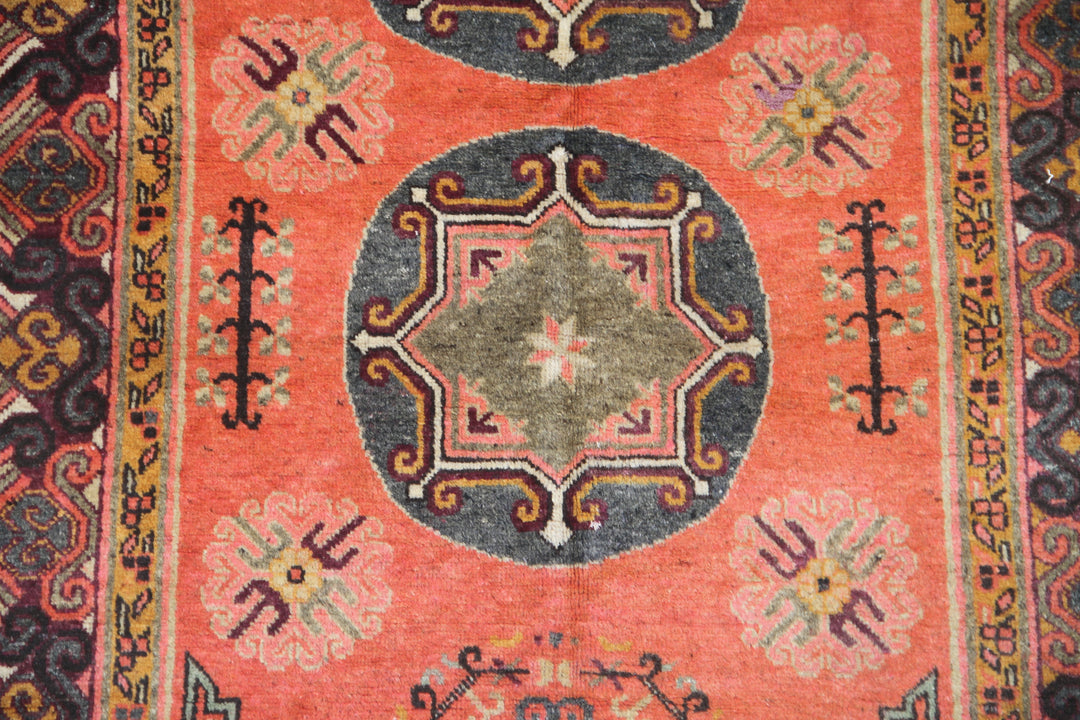 Authentic antique hand-knotted Samarkand Khotan wool area rug featuring two large grey central medallions on a deep red field with salmon brown accents