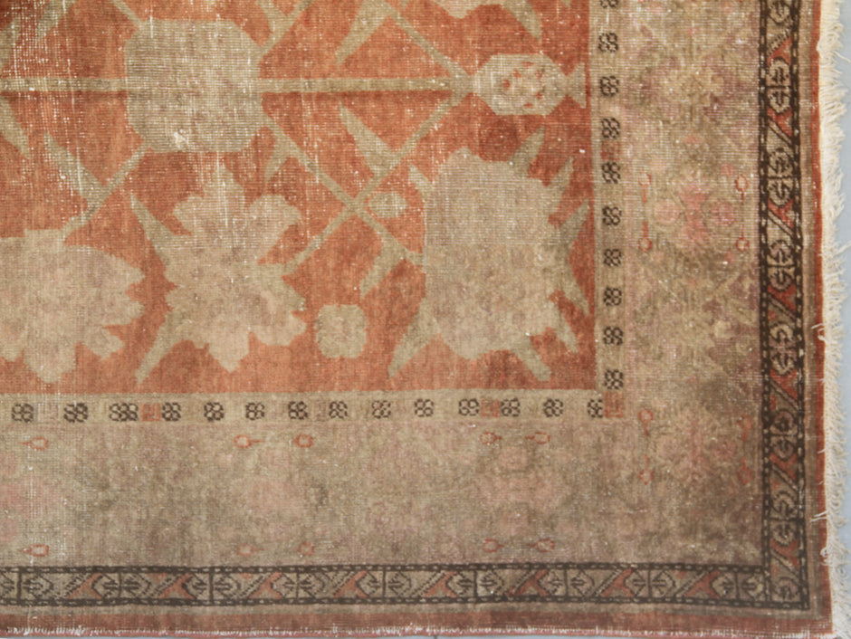 Authentic antique hand-knotted Samarkand Khotan wool area rug featuring salmon pink floral motifs on a warm rust field