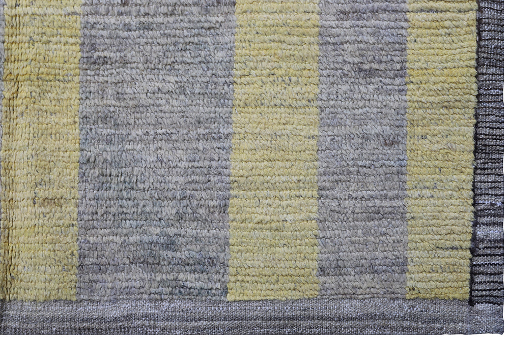 An overhead view of a massive 16x20 authentic Moroccan style long pile shag rug from the Ariana Barchi Collection, featuring a grey and yellow geometric pattern hand-woven by Hazara women weavers.