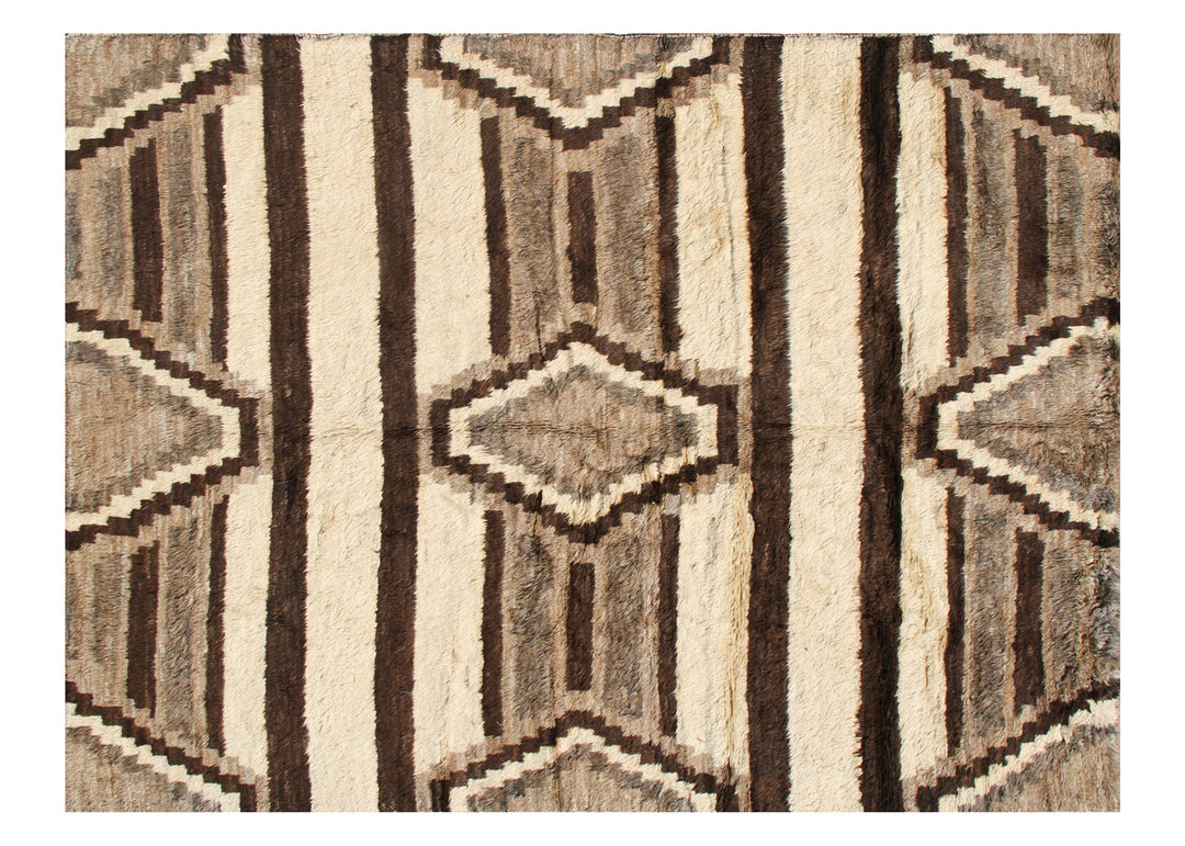 A hand-knotted rug with an Aztec design featuring undyed wool in earth tones, with a shaggy texture.