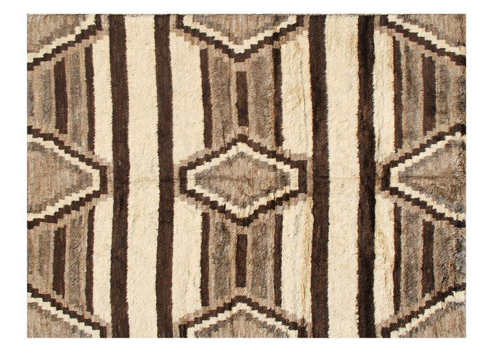 A hand-knotted rug with an Aztec design featuring undyed wool in earth tones, with a shaggy texture.