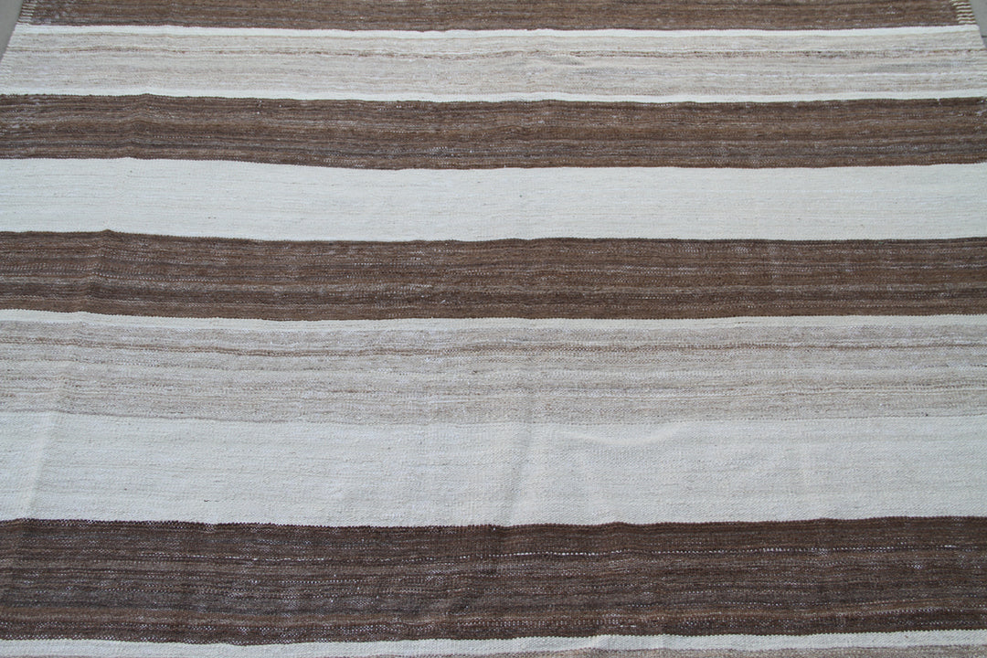 Organic modern sitting room styled with a 6x10 earth-tone brown, tan, and cream striped Afghan wool kilim from Ariana Rugs West Hollywood.