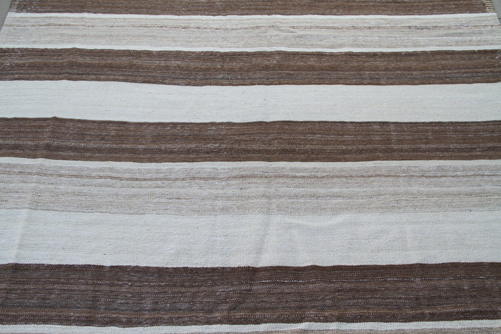 Organic modern sitting room styled with a 6x10 earth-tone brown, tan, and cream striped Afghan wool kilim from Ariana Rugs West Hollywood.