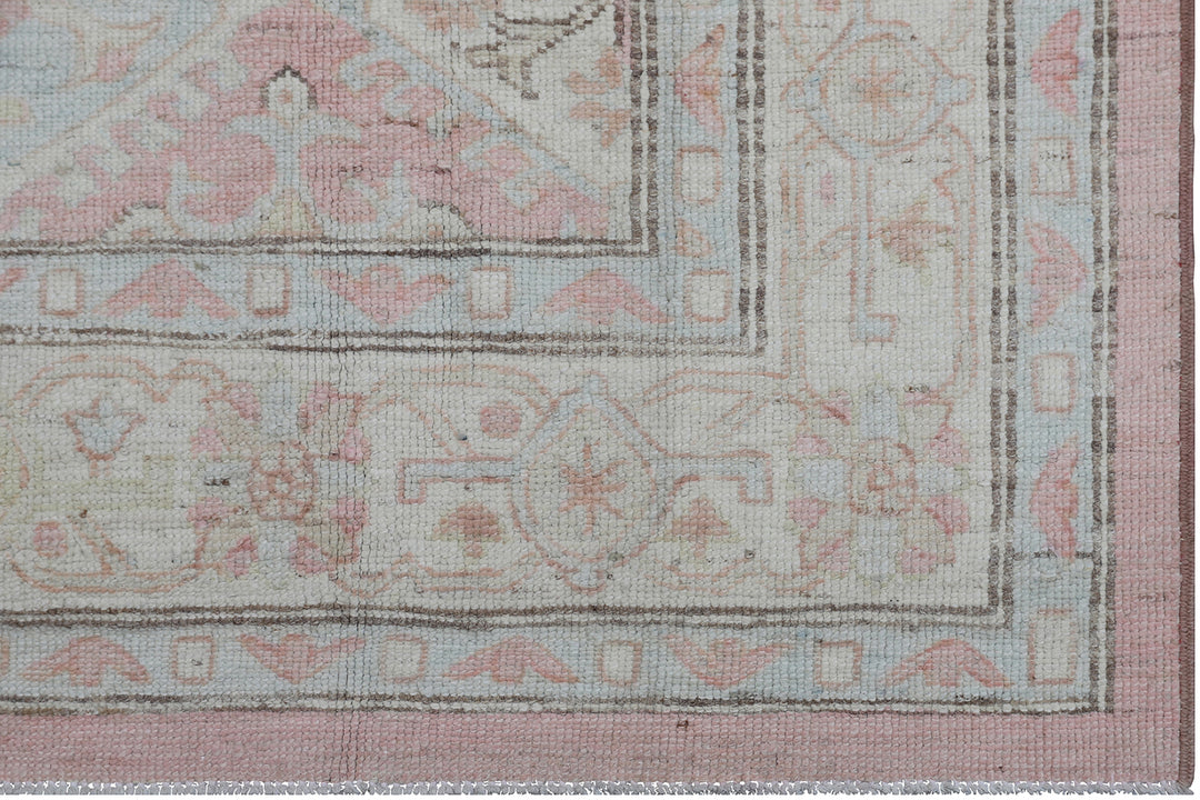 Authentic hand-knotted Afghan runner rug from the Ariana Hazara Collection, featuring geometric Caucasian motifs in pink, ivory, and blue organic wool.