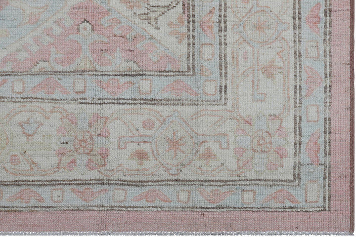 Authentic hand-knotted Afghan runner rug from the Ariana Hazara Collection, featuring geometric Caucasian motifs in pink, ivory, and blue organic wool.