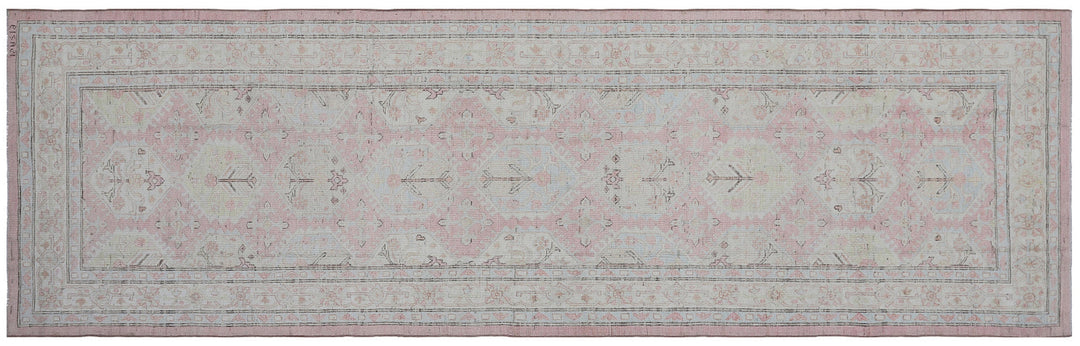 Authentic hand-knotted Afghan runner rug from the Ariana Hazara Collection, featuring geometric Caucasian motifs in pink, ivory, and blue organic wool.
