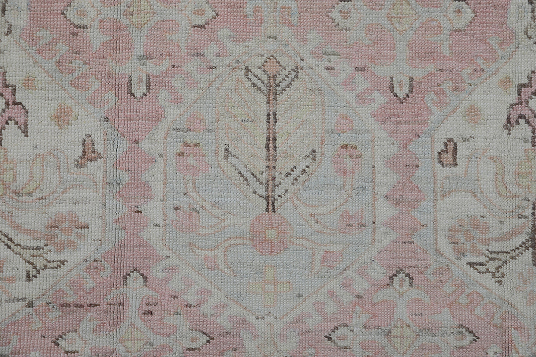 Authentic hand-knotted Afghan runner rug from the Ariana Hazara Collection, featuring geometric Caucasian motifs in pink, ivory, and blue organic wool.