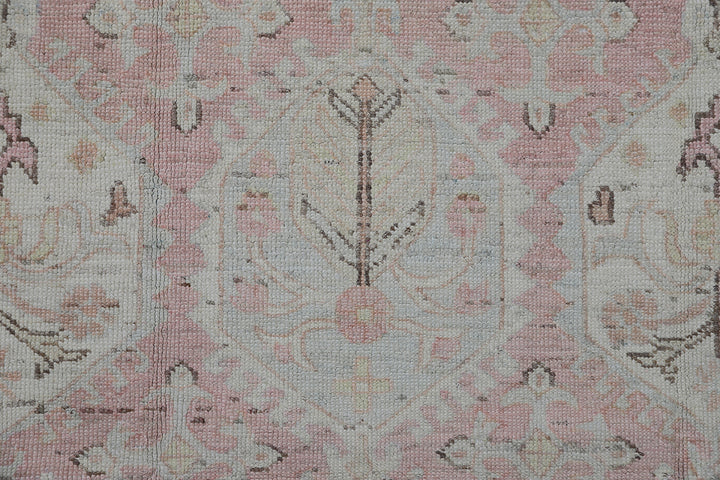 Authentic hand-knotted Afghan runner rug from the Ariana Hazara Collection, featuring geometric Caucasian motifs in pink, ivory, and blue organic wool.