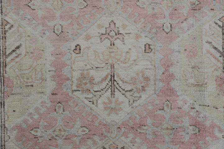 Authentic hand-knotted Afghan runner rug from the Ariana Hazara Collection, featuring geometric Caucasian motifs in pink, ivory, and blue organic wool.